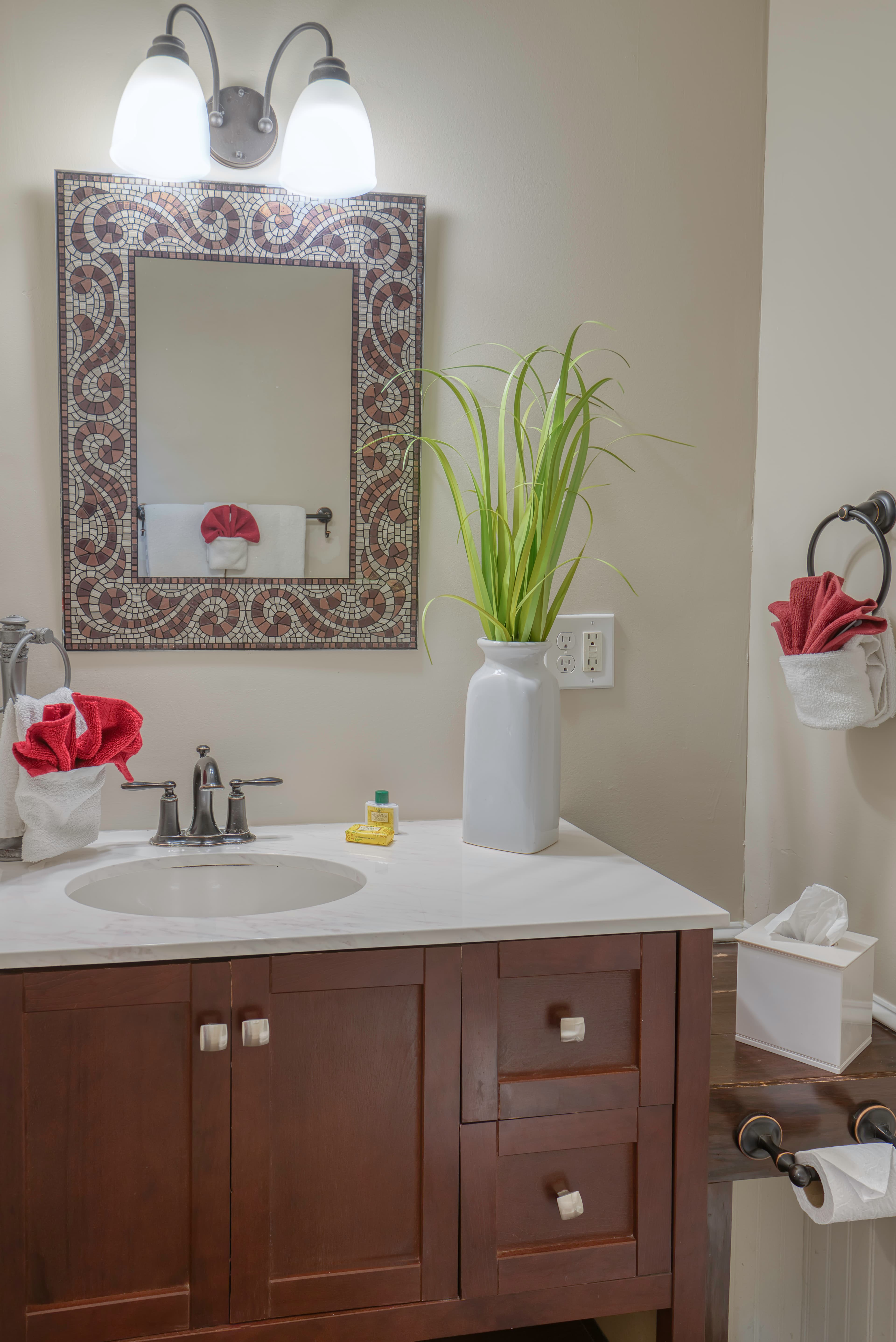 Bathroom with wooden vanity, white sink, decorative mirror with lights above