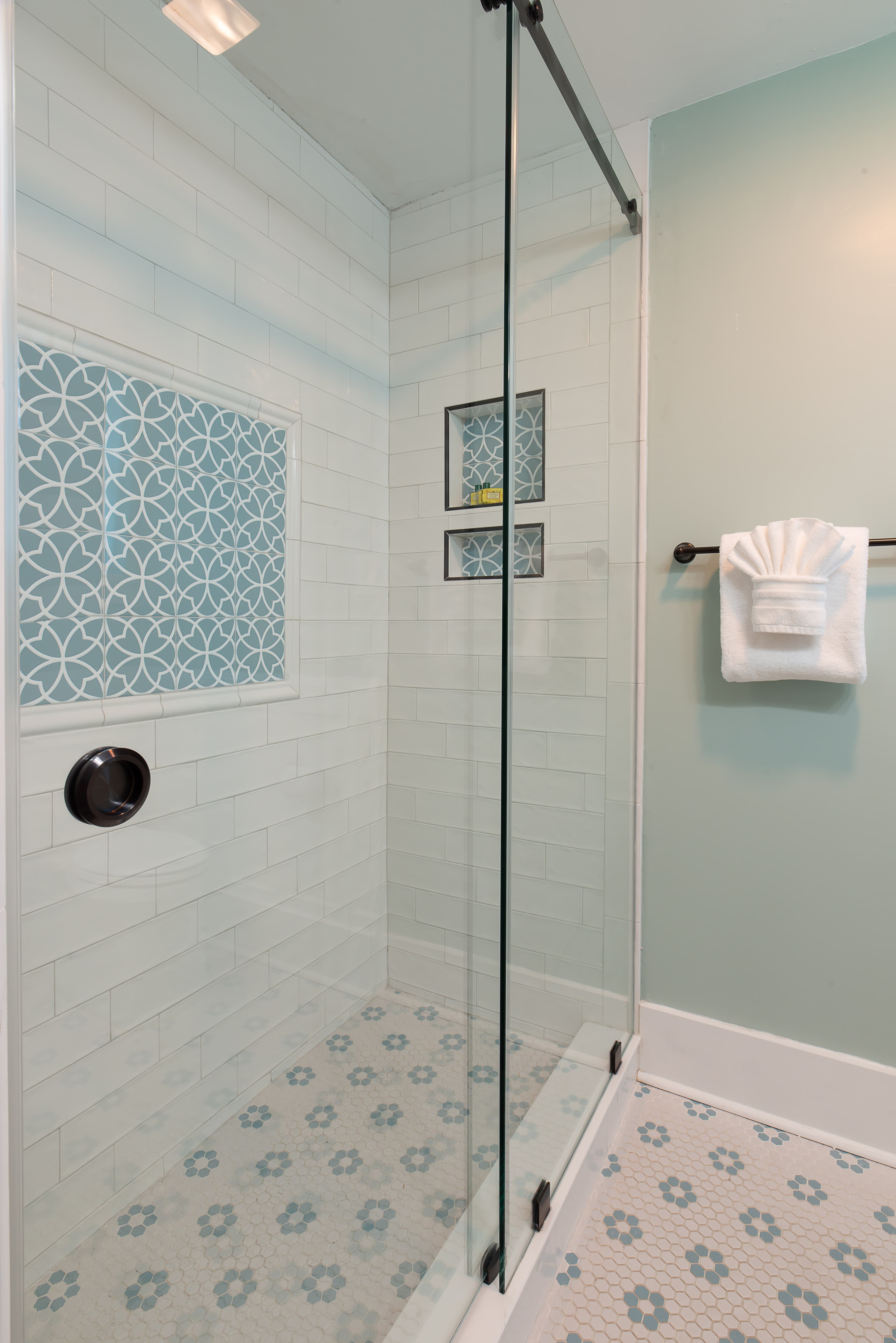 Pristine bathroom in white & shades of blue with glass-enclosed shower