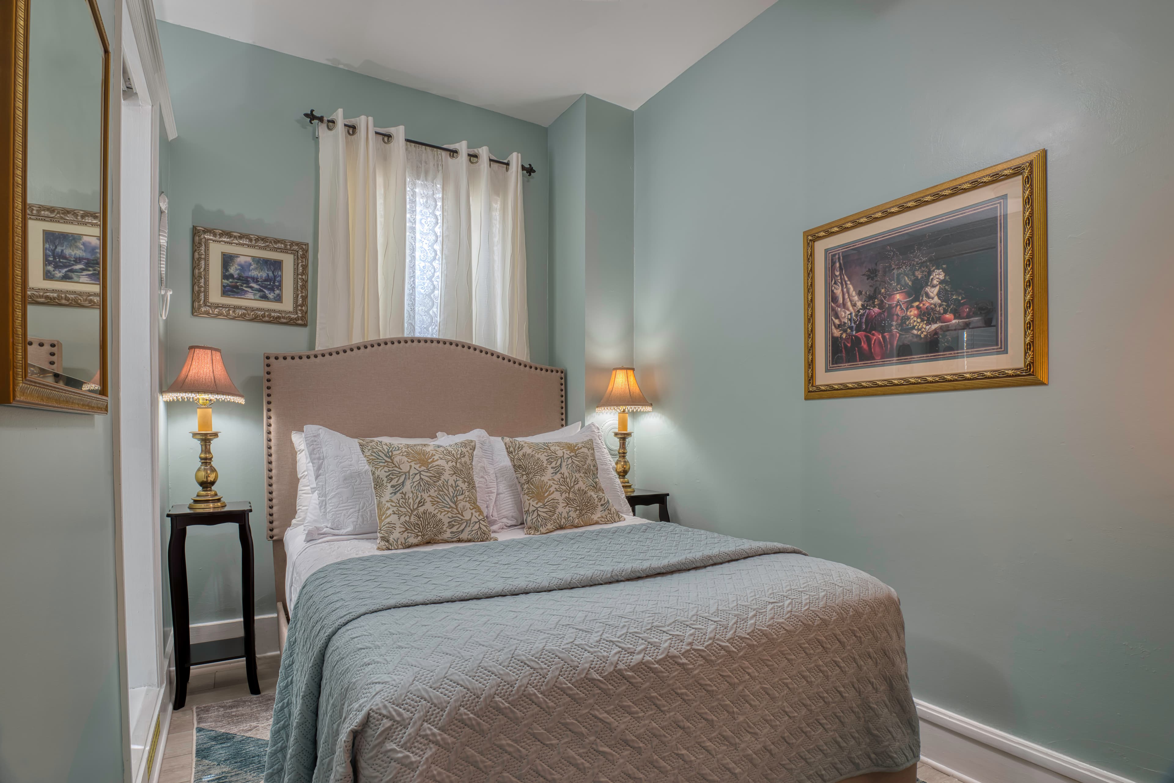 Cozy bedroom in peaceful blue and neutral shades, double bed with upholstered headboard, matching nightstands and table lamps