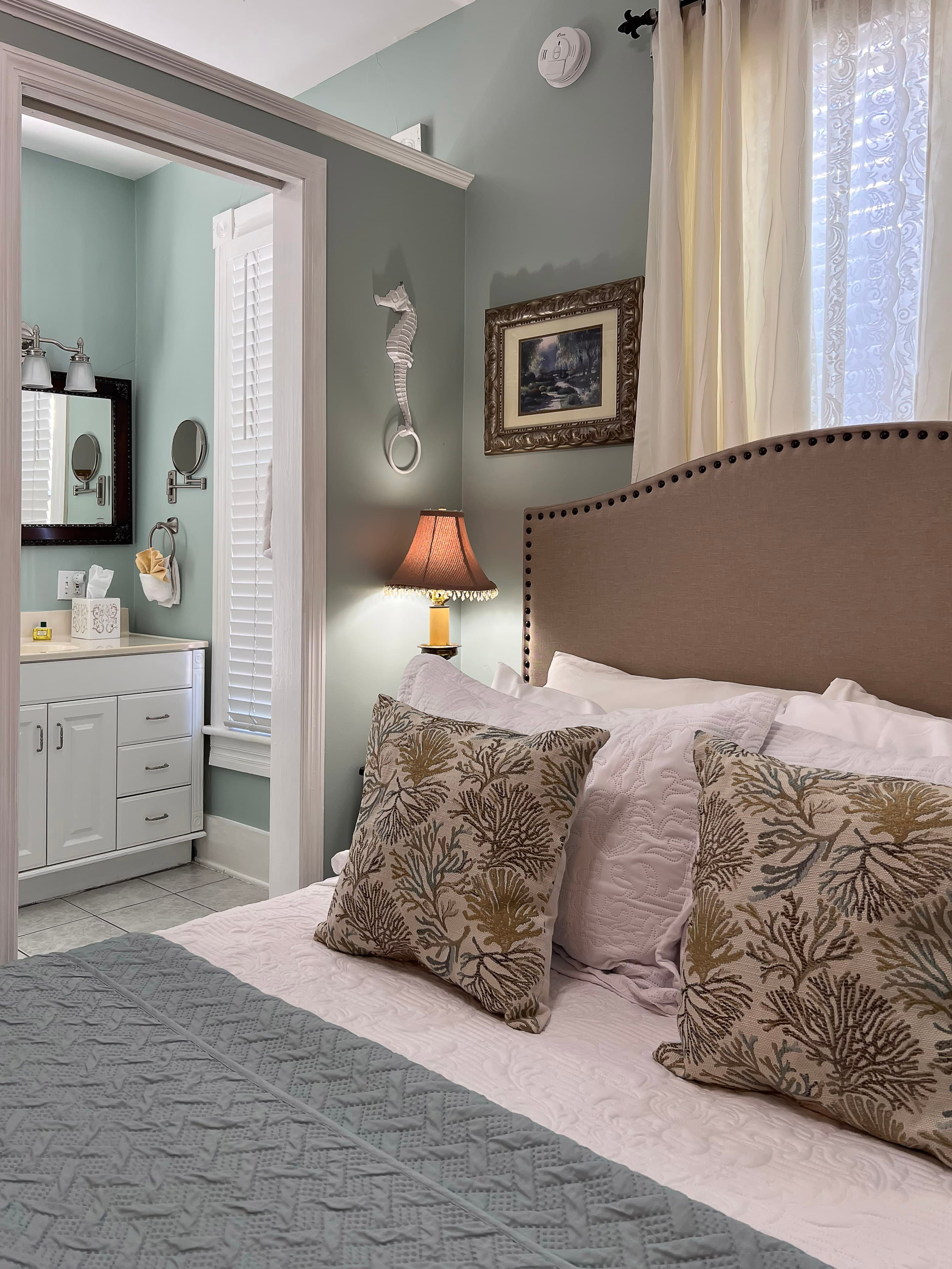 Double headboard and plump pillows in foreground and doorway to bathroom in background