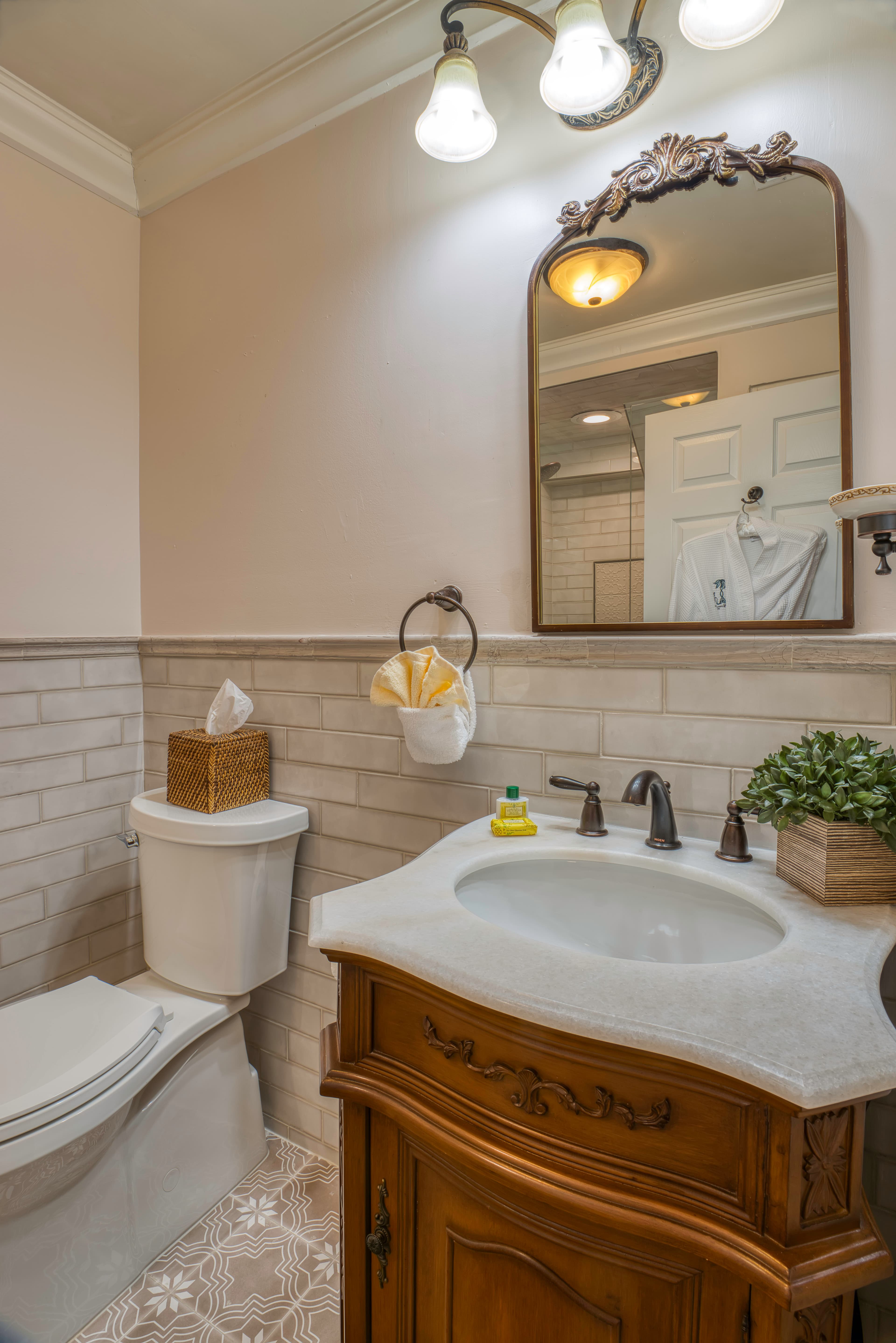 Bathroom with lovely wooden vanity with sink, tile in neutral tones, and toilet